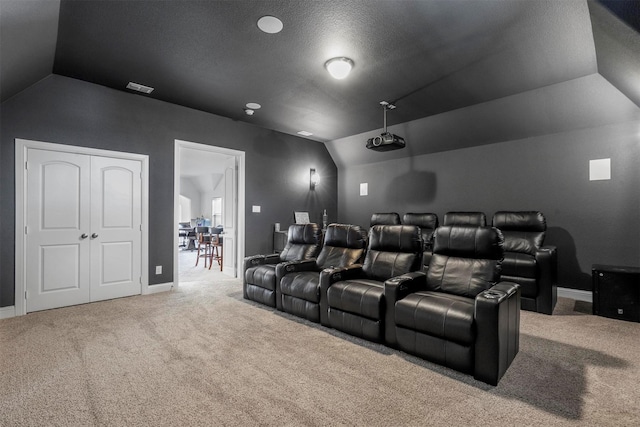 carpeted cinema room featuring lofted ceiling, a textured ceiling, visible vents, and baseboards