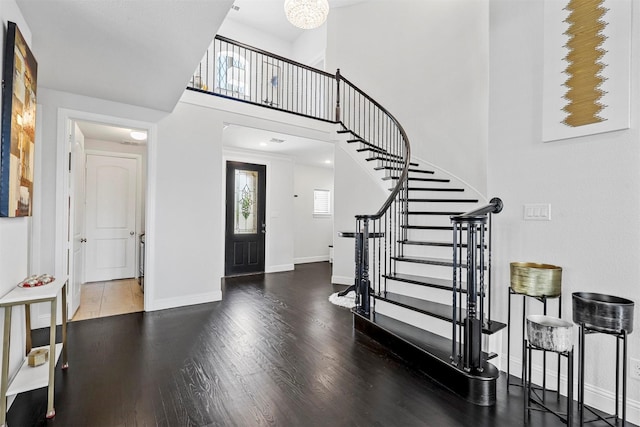 foyer with a high ceiling, wood finished floors, stairs, and baseboards