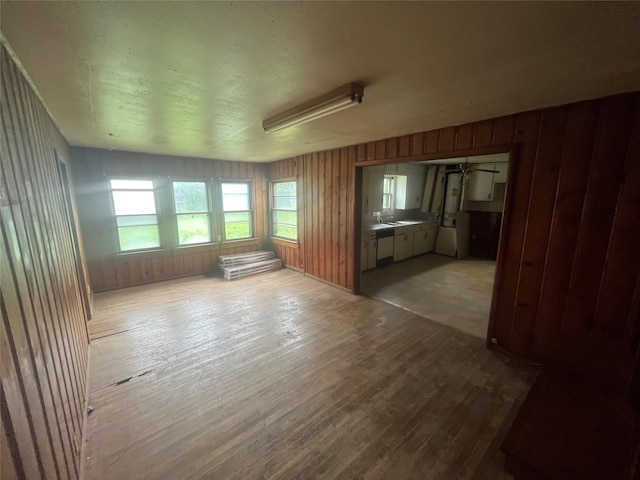 unfurnished room with light wood-type flooring and wood walls