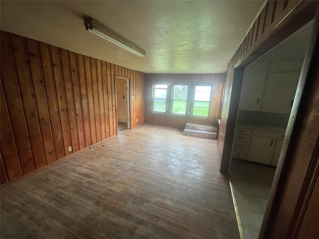 unfurnished room featuring wood-type flooring and wooden walls