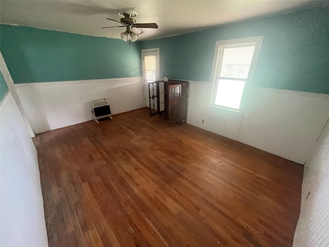 unfurnished room featuring heating unit, ceiling fan, and dark wood-type flooring