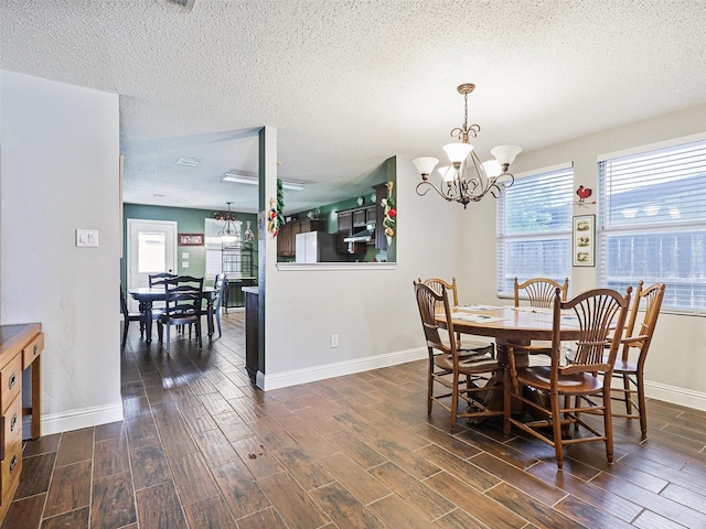 dining area with a chandelier, a textured ceiling, and dark hardwood / wood-style flooring