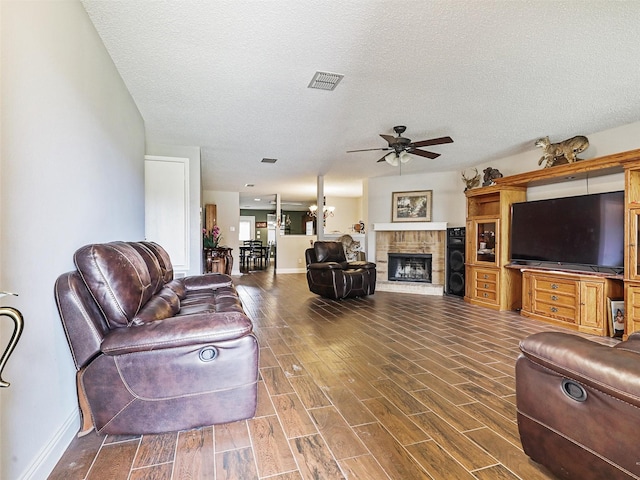 living room featuring dark hardwood / wood-style floors, ceiling fan, and a textured ceiling