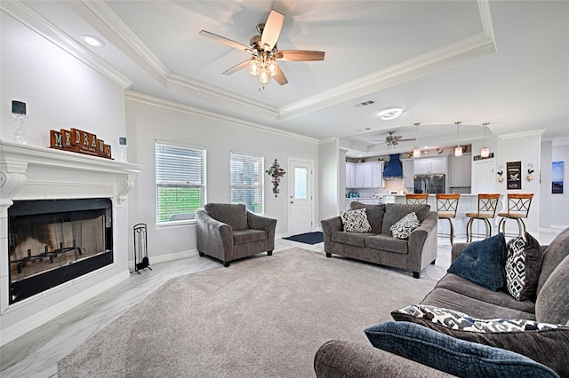 living room featuring a tray ceiling, crown molding, and ceiling fan