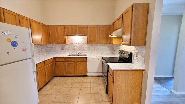 kitchen with a towering ceiling, tasteful backsplash, white appliances, light tile floors, and sink