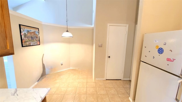 kitchen with white refrigerator, light stone countertops, light tile floors, and pendant lighting