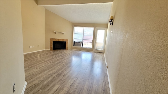 unfurnished living room with a textured ceiling, high vaulted ceiling, a fireplace, and hardwood / wood-style flooring