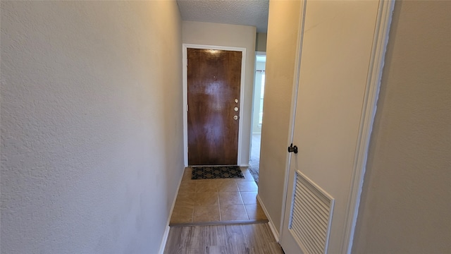 hall with a textured ceiling and wood-type flooring