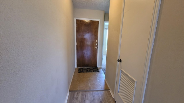 doorway to outside with light wood-type flooring and a textured ceiling