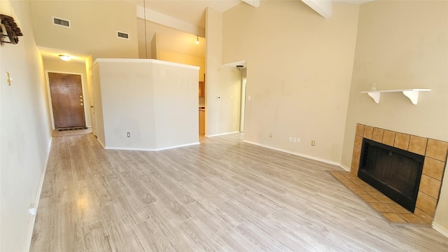 unfurnished living room with light hardwood / wood-style flooring, a fireplace, high vaulted ceiling, and beamed ceiling