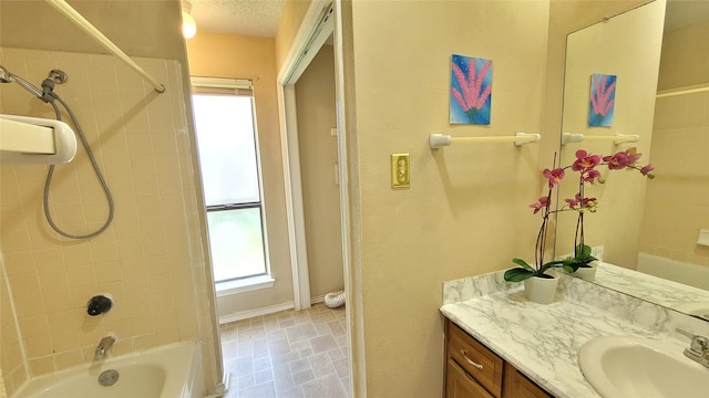 bathroom with vanity, tiled shower / bath combo, and a textured ceiling