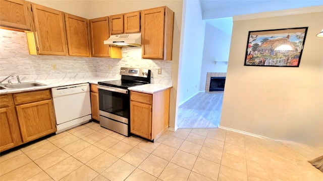 kitchen with a fireplace, stainless steel electric stove, sink, dishwasher, and light tile floors