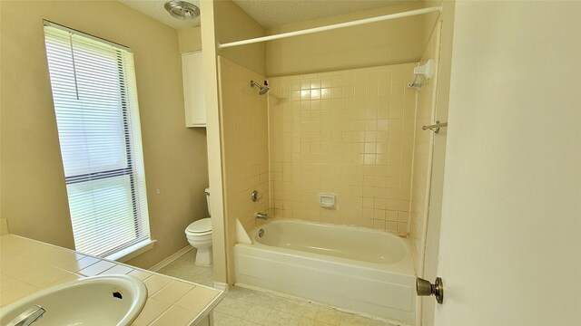 full bathroom with a textured ceiling, tile floors, tiled shower / bath combo, vanity, and toilet