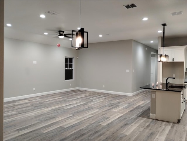 kitchen with white cabinetry, decorative light fixtures, light hardwood / wood-style floors, and sink