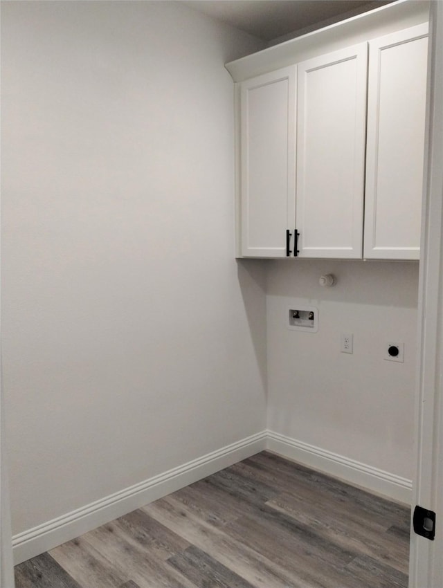 washroom featuring electric dryer hookup, washer hookup, hardwood / wood-style flooring, and cabinets