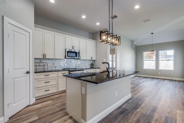 kitchen with sink, white cabinetry, hardwood / wood-style floors, stainless steel appliances, and a kitchen island with sink