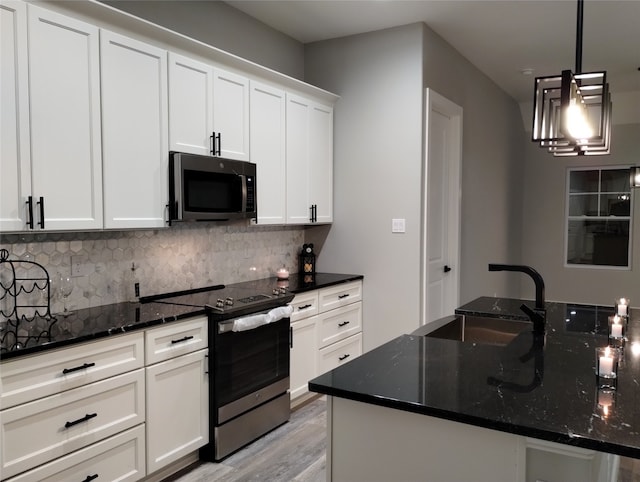 kitchen with white cabinetry, stainless steel appliances, sink, and dark stone counters