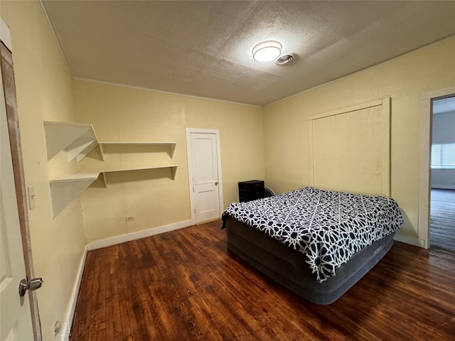 bedroom featuring a textured ceiling, crown molding, and dark hardwood / wood-style floors