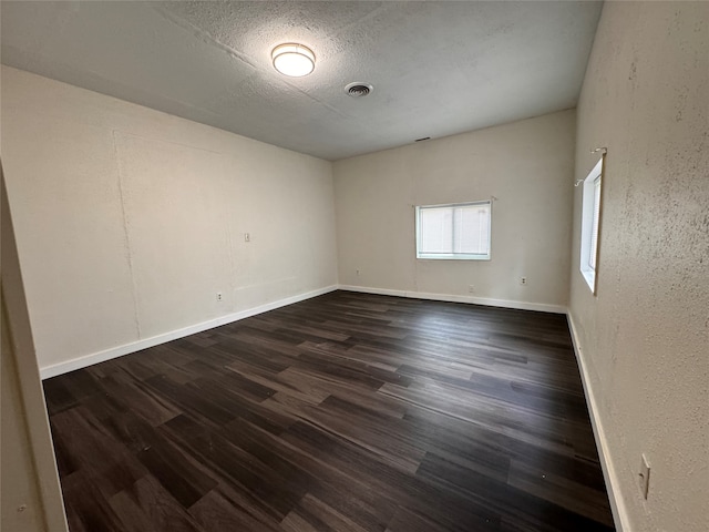 spare room with a textured ceiling and dark wood-type flooring