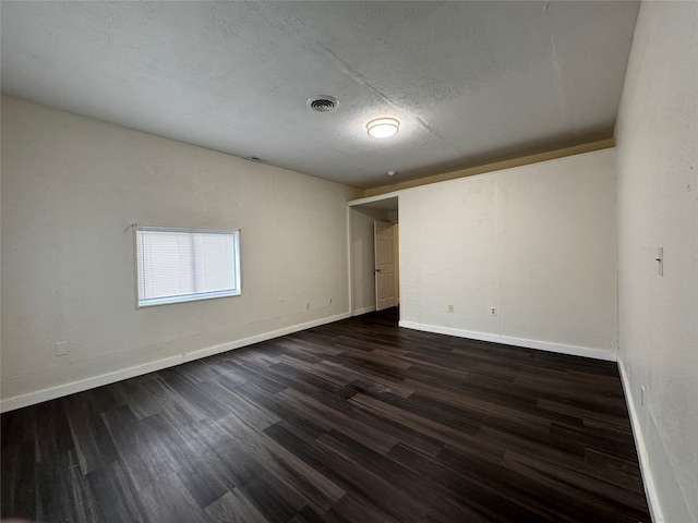 spare room with dark hardwood / wood-style flooring and a textured ceiling