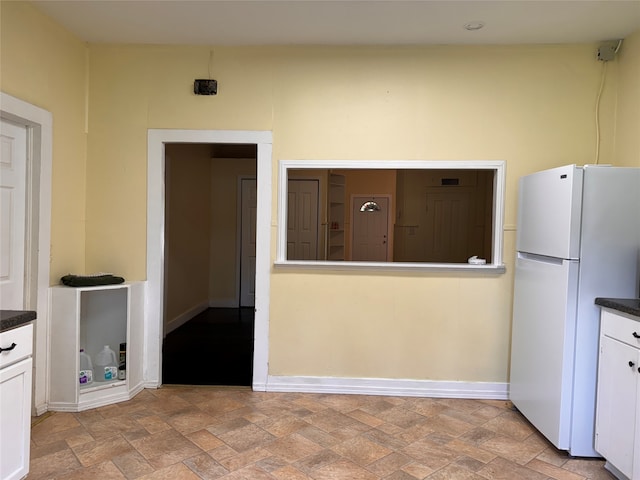 kitchen featuring white fridge and white cabinetry