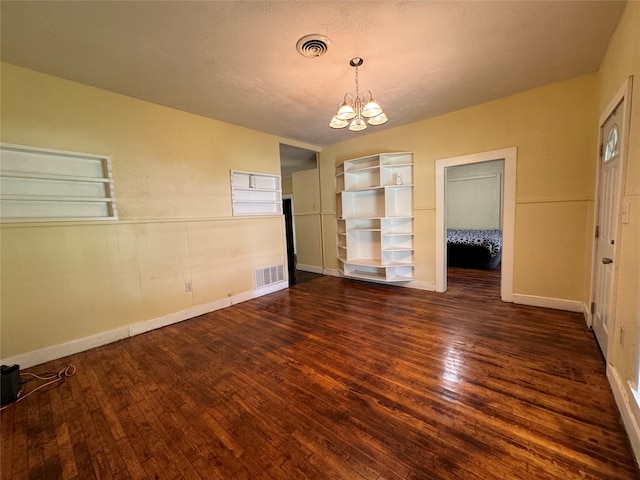 empty room featuring dark hardwood / wood-style floors, a notable chandelier, and a textured ceiling