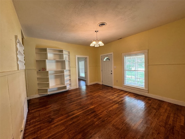 entrance foyer featuring an inviting chandelier, dark hardwood / wood-style flooring, and a textured ceiling