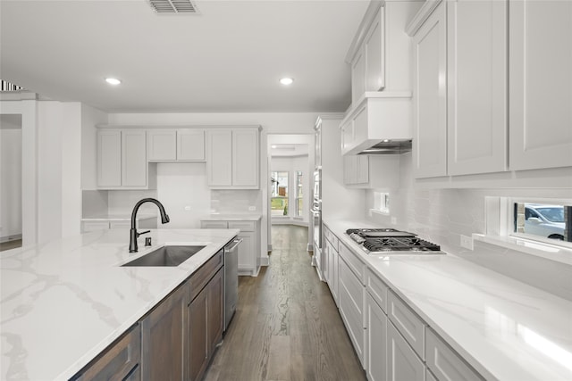 kitchen featuring tasteful backsplash, wood-type flooring, white cabinetry, appliances with stainless steel finishes, and sink