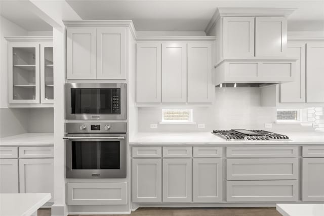 kitchen with tasteful backsplash, white cabinetry, appliances with stainless steel finishes, and hardwood / wood-style floors