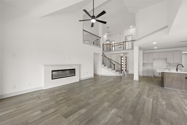 unfurnished living room featuring sink, high vaulted ceiling, wood-type flooring, and ceiling fan