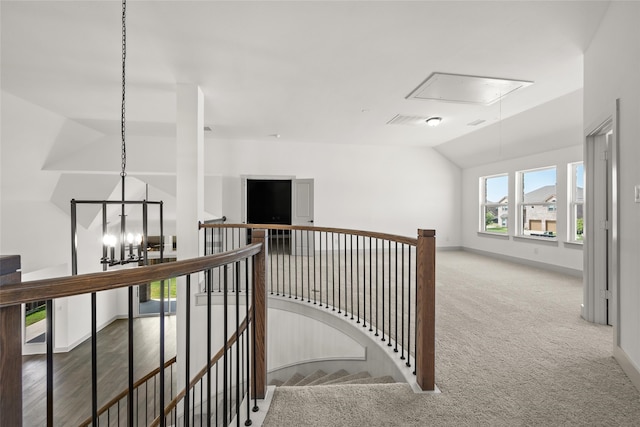 hall with carpet flooring, an inviting chandelier, and lofted ceiling