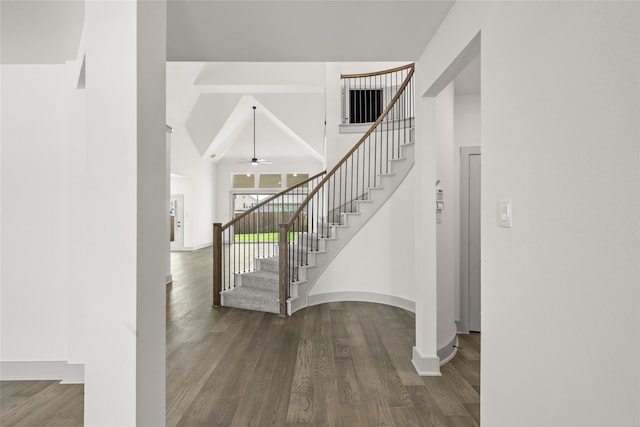 stairway featuring ceiling fan, vaulted ceiling, and wood-type flooring