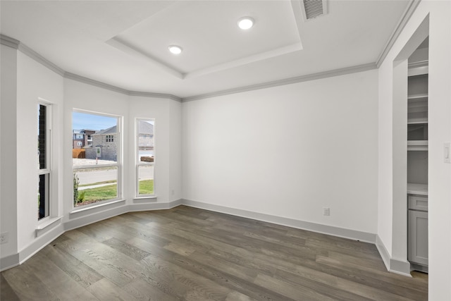 spare room featuring a tray ceiling, ornamental molding, and dark hardwood / wood-style flooring