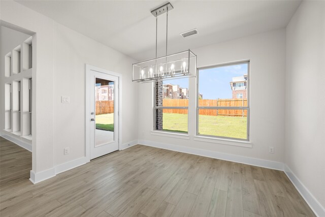 unfurnished dining area with light hardwood / wood-style floors and an inviting chandelier