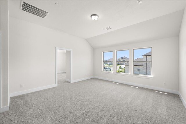 carpeted empty room featuring lofted ceiling