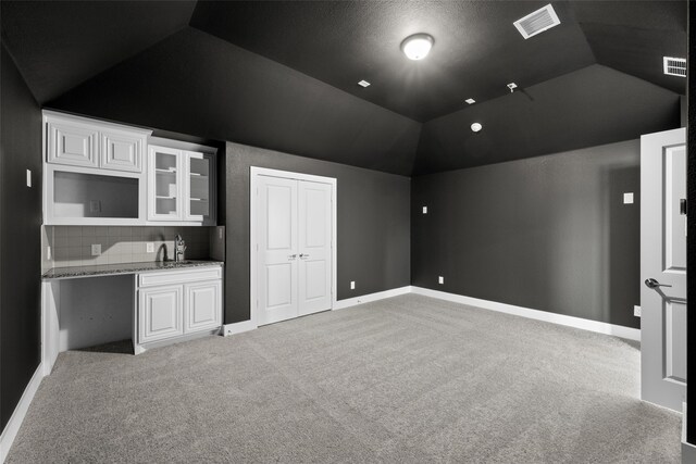 carpeted cinema room featuring sink and vaulted ceiling