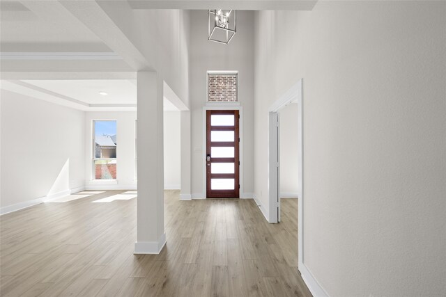 foyer entrance featuring a notable chandelier, ornamental molding, and light hardwood / wood-style flooring