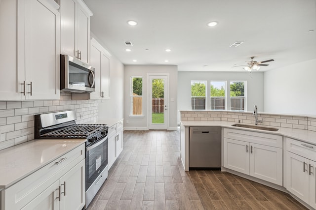 kitchen with sink, stainless steel appliances, dark hardwood / wood-style floors, backsplash, and white cabinets