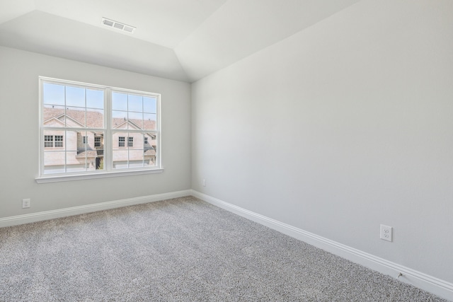 spare room featuring carpet and lofted ceiling