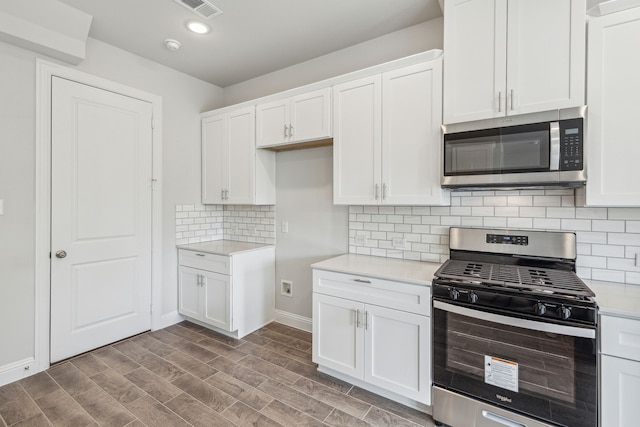 kitchen featuring white cabinets, dark hardwood / wood-style floors, decorative backsplash, and appliances with stainless steel finishes