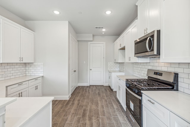 kitchen featuring decorative backsplash, wood-type flooring, stainless steel appliances, and white cabinetry