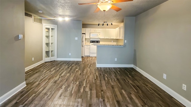 interior space with white cabinets, white appliances, ceiling fan, dark wood-type flooring, and a textured ceiling