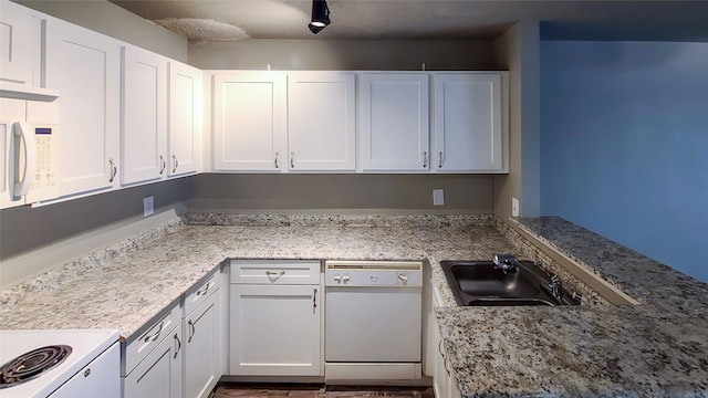 kitchen with light stone counters, sink, white cabinets, and white appliances