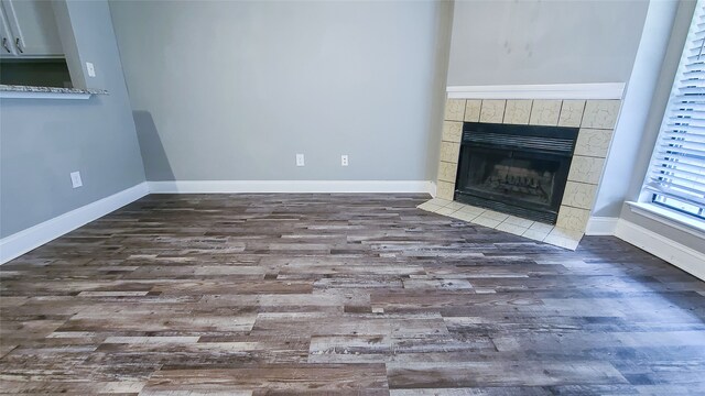 unfurnished living room with dark wood-type flooring and a tile fireplace