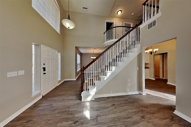 entrance foyer featuring a towering ceiling, an inviting chandelier, and dark hardwood / wood-style flooring