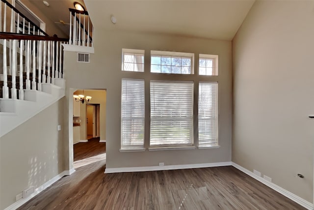 interior space with dark wood-type flooring, a high ceiling, and an inviting chandelier