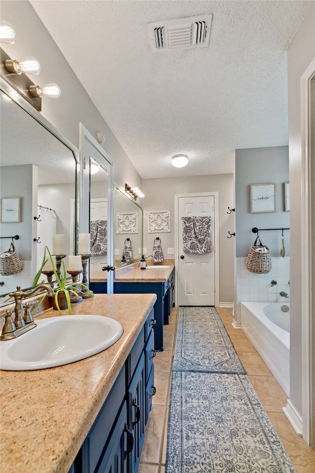 bathroom with tile floors, vanity, a bath, and a textured ceiling