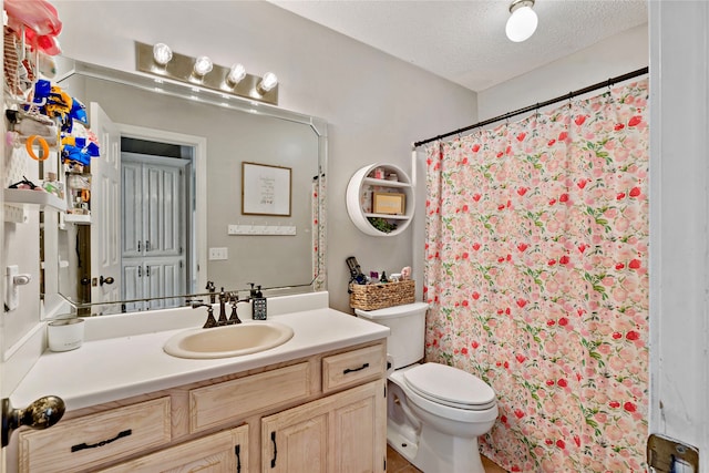 bathroom featuring tile flooring, vanity with extensive cabinet space, a textured ceiling, and toilet