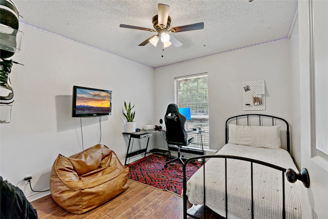 bedroom with a textured ceiling, wood-type flooring, and ceiling fan