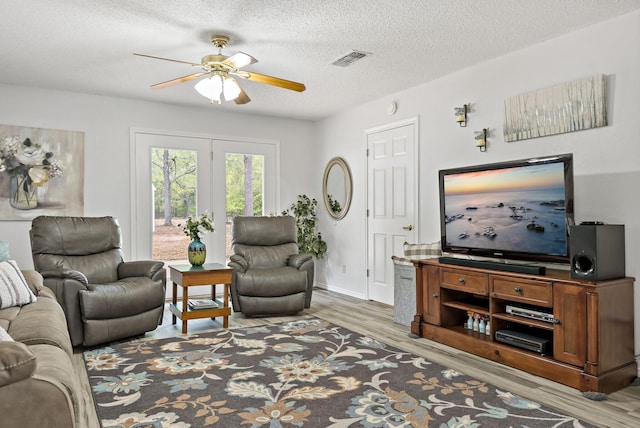 living room featuring ceiling fan, wood-type flooring, and a textured ceiling